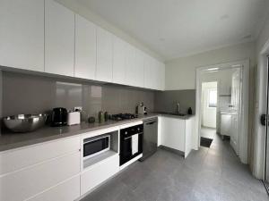una cocina con armarios blancos y fregadero en 2 Bedroom Darling Harbour - Pyrmont 2 E-Bikes Included, en Sídney