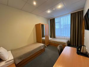 ein Hotelzimmer mit 2 Betten und einem Tisch in der Unterkunft Hotel - cafe Naujoji Akmenė in Naujoji Akmenė