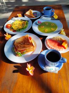 einen Holztisch mit Tellern aus Essen und einer Tasse Kaffee in der Unterkunft Sukma Guest House in Ubud