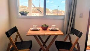 einen kleinen Holztisch mit zwei Stühlen und einem Fenster in der Unterkunft Apartamento Casal beira mar, Ventos de Sibaúma in Tibau do Sul