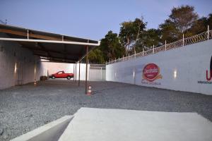 a garage with a red car parked under a wall at Residencial Rosê - flats mobiliados in Ubajara