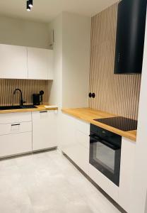 a kitchen with white cabinets and a black stove at AK Apartments 2 in Warsaw