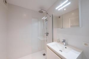 a white bathroom with a sink and a shower at Luxury Apartment With Free Parking in Ostend