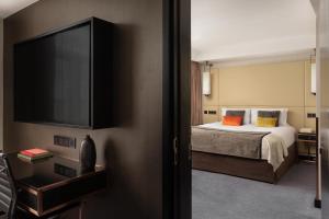 a bedroom with a bed and a flat screen tv at Montcalm Royal London House, London City in London