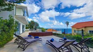 a patio with chairs and a table and the ocean at Villa Madeira by LovelyStay in Caniço