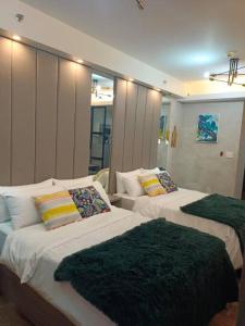 - une chambre avec 2 lits avec des couvertures vertes dans l'établissement Cozy Family Nook at Makati, à Manille