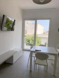 Camera bianca con tavolo, sedie e finestra di Verde Blu Vacanze Suites a Porto Cesareo