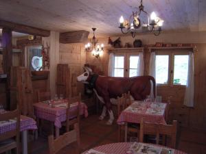 a cow standing in a dining room with tables at Au Bois de Lune in Châtel