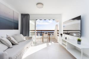 een witte woonkamer met een witte bank en een tafel bij Home2Book Stylish Studio Ocean View Tabaiba in Tabaiba