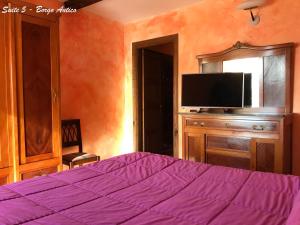 - une chambre avec un lit violet et une télévision dans l'établissement Albergo Diffuso Locanda Specchio Di Diana, à Nemi