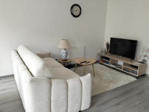 - un salon avec un canapé blanc et une télévision dans l'établissement La Provence vous Attend - 2ème étage, à Digne-Les-Bains