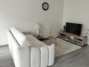 a living room with a white couch and a tv at La Provence vous Attend - 2ème étage in Digne-les-Bains