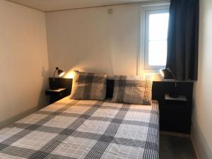 een slaapkamer met een bed met een geruite sprei en een raam bij Vakantiehuis voor 4 personen in Opheusden