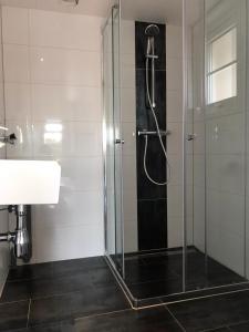 a glass shower in a bathroom with a sink at Vakantiehuis voor 4 personen in Opheusden