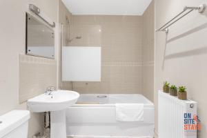 a white bathroom with a sink and a tub and a toilet at OnSiteStays - Cosy 2-Bedroom Apartment with Free Parking, Wi-Fi & London Links in Northfleet