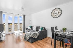 a living room with a couch and a clock on the wall at OnSiteStays - Cosy 2-Bedroom Apartment with Free Parking, Wi-Fi & London Links in Northfleet