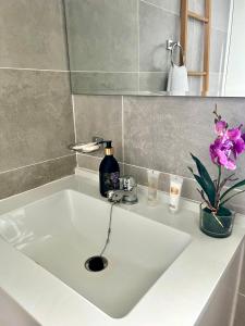 a white sink with a bottle of soap and flowers at Sarona LoLa E206 in Gaborone