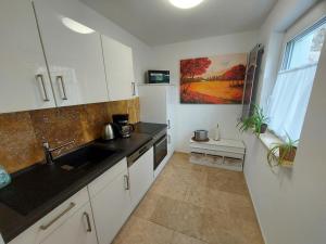 a kitchen with white cabinets and a sink at Ferienwohnung und Zimmer zum Donaublick in Kelheim