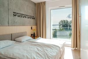 a bedroom with two beds and a large window at ARCHE Fabryka Samolotów w Mielnie in Mielno