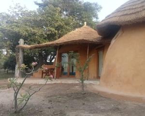 eine Hütte mit einem Strohdach und einem Tisch in der Unterkunft Les Collines De Niassam in Palmarin