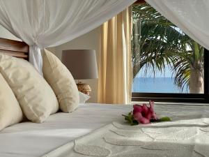 sypialnia z łóżkiem z kwiatem w obiekcie Chalets Bougainville w mieście Takamaka