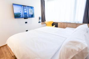 een slaapkamer met een wit bed en een tv aan de muur bij Hotel Lonca - Superior in Škofja Loka