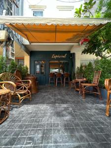une terrasse avec des chaises, des tables et un parasol dans l'établissement Petit Espace Boutique Hostel, à Vientiane