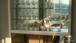 una vitrina de cristal con copas de vino y un sofá en Apartamento Novo Centro de Gramado, en Gramado