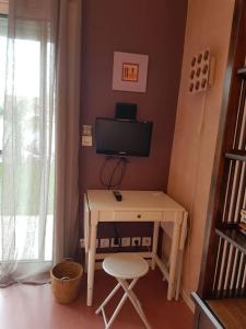 a room with a desk with a television and a stool at Chez Hélène in Bordeaux