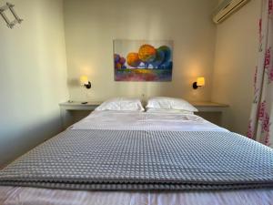 埃爾米奧的住宿－佐伊酒店，卧室内的一张床铺,墙上有绘画作品