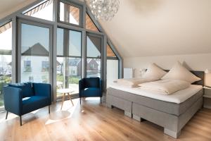 a bedroom with a bed and two blue chairs at Ostsee - Reetdachhaus Nr 38 "RIKE" im Strand Resort in Heiligenhafen