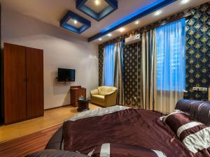 a bedroom with a bed and a chair and a television at Cron Hotel in Moscow