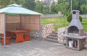 a wood fired oven and a picnic table with an umbrella at Gorgeous Home In Labin With Kitchen in Labin