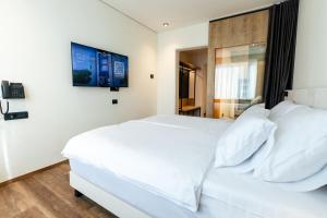 1 dormitorio con 1 cama blanca y TV en la pared en Hotel Lonca - Superior, en Škofja Loka