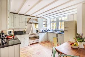uma cozinha com armários brancos e uma mesa de madeira em Fern House em Dorchester