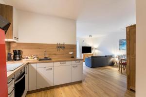 a kitchen with white cabinets and a living room at Seegaard Wohnung 3 in Husby
