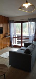 uma sala de estar com um sofá e uma grande janela em Studio Le Lacuzon avec piscine et tennis extérieurs em Les Rousses