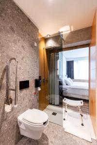 a bathroom with a toilet and a shower and a bed at Hotel Lonca - Superior in Škofja Loka