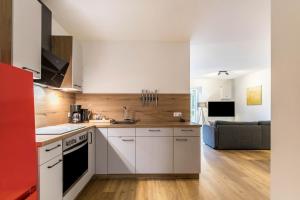 a kitchen with white cabinets and a living room at Willewatt Wohnung 1 in Husby +11 photos