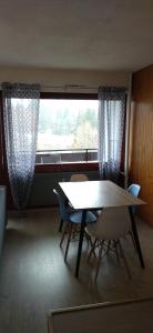 a dining room with a table and chairs and a window at Studio Le Lacuzon avec piscine et tennis extérieurs in Les Rousses