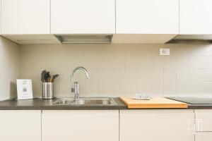 una cucina con lavello in acciaio inossidabile e mobili bianchi di HT - Elegante mini in Prato della Valle a Padova