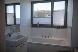 a bathroom with a tub and a sink and two windows at Ostsee - Reetdachhaus Nr 37 "RENATE" im Strand Resort in Heiligenhafen
