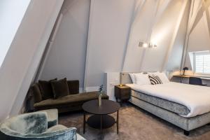 um quarto com uma cama, um sofá e uma cadeira em Maison ELLE Amsterdam em Amsterdã