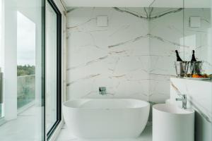 a white bathroom with a tub and a sink at ARCHE Fabryka Samolotów w Mielnie in Mielno