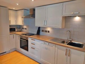 a white kitchen with white cabinets and a sink at Finest Retreats - Little Dunley - Lake View in Bovey Tracey