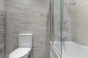 uma casa de banho com um WC e uma cabina de duche em vidro. em Gorgeous 3-bedroom in London - Sleeps 8 em Londres