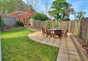 a patio with a table and chairs in a yard at Finest Retreats - Little Dunley - Vine Lodge in Bovey Tracey