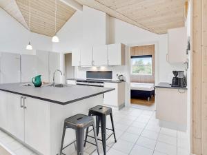 una cocina con armarios blancos y 2 taburetes. en 24 person holiday home in Idestrup, en Bøtø By
