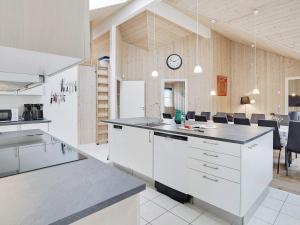una cocina con armarios blancos y un reloj en la pared en 24 person holiday home in Idestrup, en Bøtø By