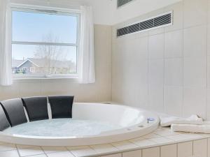 baño blanco con bañera y ventana en 24 person holiday home in Idestrup, en Bøtø By